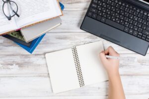 Workplace with laptop, notepad, pen and books
