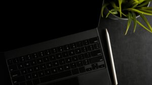 Tablet with keyboard and stylus pen on dark workspace.