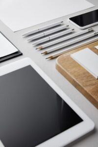 business cards on wooden board, pens, pencils, paper, smartphone and digital tablet