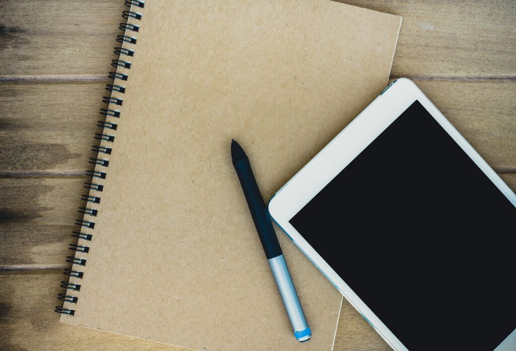 Notebook with tablet and pen on wooden table