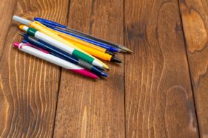 different pens on wooden background